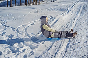 Happy woman having fun during rolling down the mountain slope on sled. Winter sports with snow. People riding a sledge