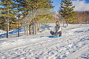 Happy woman having fun during rolling down the mountain slope on sled. Winter sports with snow. People riding a sledge