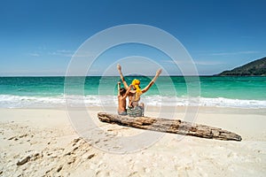 Happy woman having fun with son on a tropical beach, enjoying summer holidays, raising hands up. Tourism, family travel concept