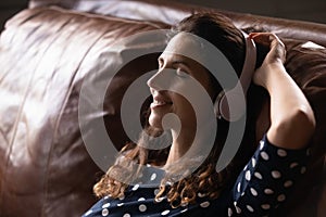 Happy woman in headphones listen to music on couch