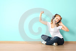 Happy woman in headphones listening to music in a room with a b