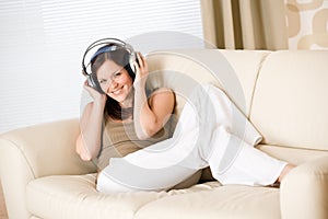 Happy woman with headphones on sofa in lounge