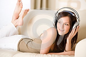 Happy woman with headphones on sofa in lounge