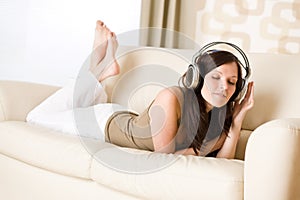 Happy woman with headphones on sofa in lounge