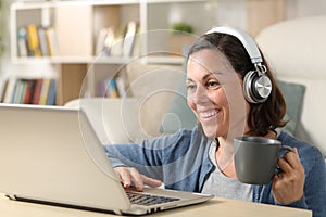 Happy woman with headphones watching video on laptop at home