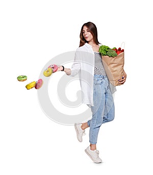 Happy woman with healthy food throw away unhealthy donuts