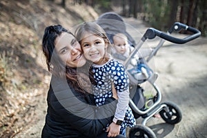Happy woman with her adorable young daughters in the forest