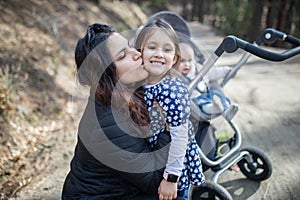 Happy woman with her adorable young daughters in the forest