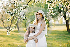 A happy woman and her daughter in a blooming spring garden. The concept of the Mother`s Day holiday