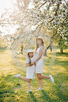 A happy woman and her daughter in a blooming spring garden. The concept of the Mother`s Day holiday