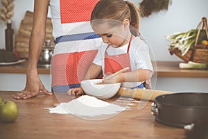 Happy woman and her daughter are kneading the dough and baking cookies for a delicious family feasting. Christmas, New