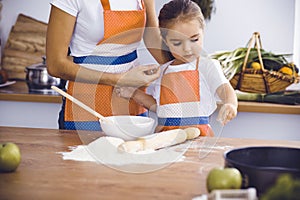 Happy woman and her daughter are kneading the dough and baking cookies for a delicious family feasting. Christmas, New