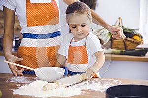 Happy woman and her daughter are kneading the dough and baking cookies for a delicious family feasting. Christmas, New