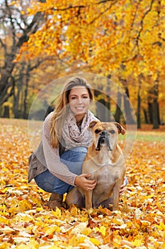 Happy woman with her dog sitting in autumn leaves
