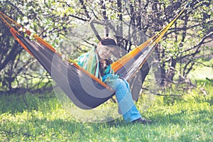 Happy woman with her funny dog, dachshund is relaxing in a hammock