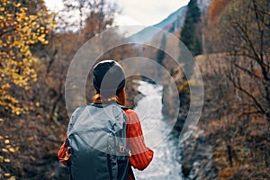 happy woman hiker with backpack on his back near mountain river on nature back view