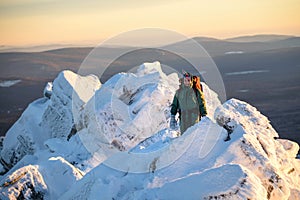 Happy Woman hiker with backpack standing on the mountain peak abd smiling at cold winter day. Female hero and active