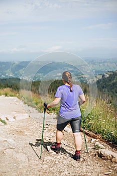 Happy woman hiker with backpack standing on the slope of mountain ridge against mountains. 30s Women holding hiking