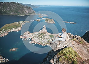 Happy woman hiker enjoying scenic view at the top of Reinebringen hike above Reine village in the Lofoten archipelago, travel to