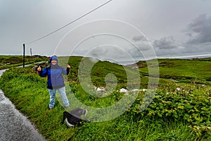 Happy woman hiker starting the coastal walk route from Doolin to the Cliffs of Moher on a rainy day