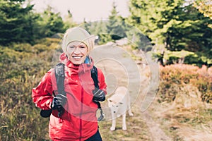 Happy woman hiking walking with dog in autumn forest