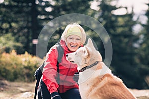 Happy woman hiking and walking with dog in autumn forest, friend