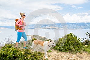 Happy woman hiking walking with dog on seaside trail