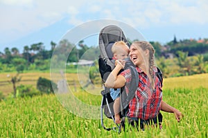 Happy woman hold child in backpack baby carrier