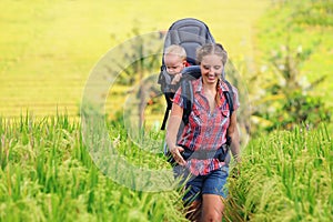 Happy woman hold child in backpack baby carrier