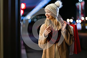 Happy woman hold shopping bags and smiling on city street. Christmas shopping, winter sale concept.