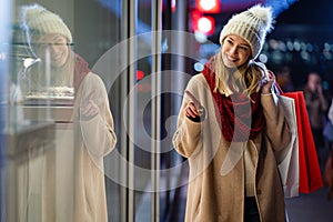 Happy woman hold shopping bags and smiling on city street. Christmas shopping, winter sale concept.