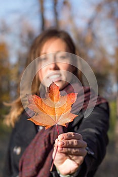 Happy woman holding autumn leaf in park