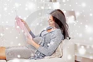 Happy woman holding baby girls bodysuit at home