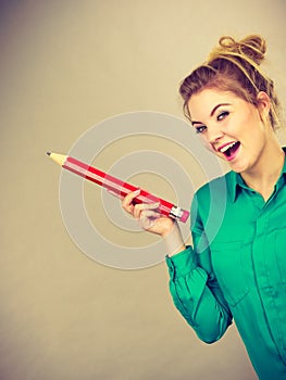 Happy woman holding big oversized pencil