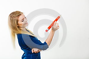 Happy woman holding big oversized pencil