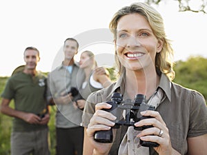 Happy Woman Holding Binoculars With Friends In Background