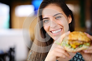 Happy woman holding burger in a restaurant