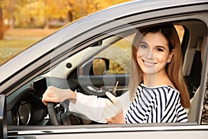 Happy woman holding car key in auto. Driving test