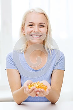 Happy woman holding fish oil capsules at home