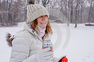 Happy woman holding flask outside in snow
