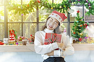 Happy woman holding gift boxes with Merry Christmas decoration in window background