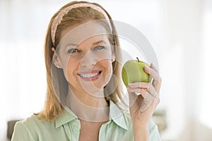 Happy Woman Holding Granny Smith Apple At Home