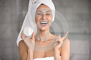 Happy woman holding jar of anti-ageing cream beauty treatment