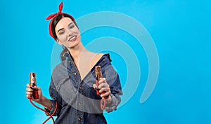 The happy woman holding jumper cables on the blue background.