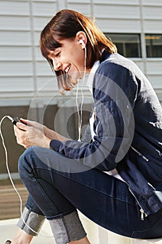 Happy woman holding mobile phone with earphones