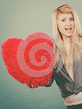 Happy woman holding red pillow in heart shape