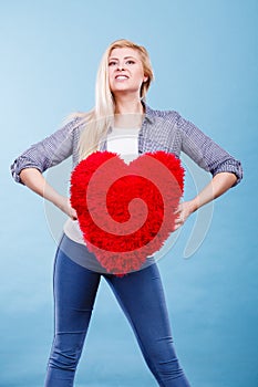 Happy woman holding red pillow in heart shape