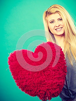 Happy woman holding red pillow in heart shape