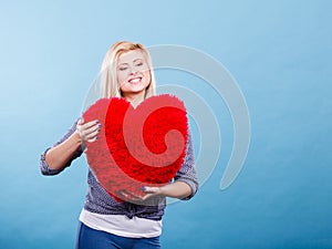 Happy woman holding red pillow in heart shape