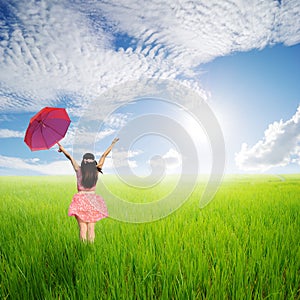 Happy Woman holding red umbrella in green rice fields in sun sky